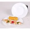 A white plate with a shrimp and corn skewer and a second white plate in the background. Anteprima dell’immagine prodotto