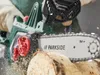 A person is using a cordless chainsaw to cut a log. Produktbild-Vorschau