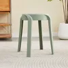 A single green stool is shown in a room with a carpet and a shelf in the background. Voir les images du produit