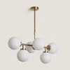 A modern chandelier with a gold metal frame and white glass globes. Produktbild-Vorschau