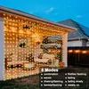 String lights are draped over a covered patio area, illuminating outdoor furniture and a fence. Anteprima dell’immagine prodotto