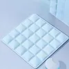 A light blue quilted mat with diamond-shaped sections is shown on a light gray surface. A portion of a stack of translucent blue panels is visible in the background. Produktbild-Vorschau