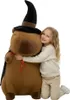 A young girl is hugging a large stuffed capybara wearing a wizard hat and cape. Náhľad obrázku produktu