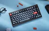 A keyboard is placed on a blue surface, with a pair of glasses and some small red objects scattered around. Produktbild-Vorschau
