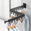 A black wall-mounted folding clothes rack with clothes hanging on it, positioned near a window with white curtains. Produktbild-Vorschau