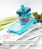 A manual vegetable slicer with a hopper attachment is shown on a white platter, with sliced radishes in the foreground and celery stalks in the background. Produktbild-Vorschau