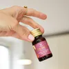 A hand holding a small bottle of liquid supplement. Produktbild-Vorschau