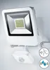 A white LED floodlight with a motion sensor attached, mounted on a wall. Produktbild-Vorschau