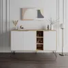 A modern sideboard with white doors and a natural oak-effect frame, standing on black hairpin legs. It's styled with decorative items and a piece of abstract art hangs on the wall above it. A floor lamp is positioned to the right. Produktbild-Vorschau