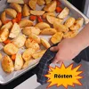 A hand is holding a baking tray with potatoes and carrots, ready to be roasted. Produktbild-Vorschau