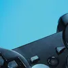 A close-up of a black video game controller against a bright blue background. Produktbild-Vorschau