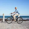 A man rides an electric bicycle along a paved path by the ocean. Produktbild-Vorschau