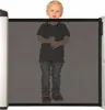 A young child is standing behind a black mesh baby gate. Náhľad obrázku produktu