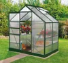 A greenhouse filled with plants in a garden setting. Produktbild-Vorschau