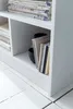A close-up view of a white shelf unit with books and CDs on it. Produktbild-Vorschau