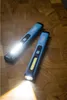 Two blue LED pen lights are placed on a wooden surface, with one light illuminating the area in front of it. Náhled obrázku produktu