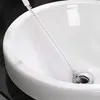 A cleaning brush is being used to remove hair from a sink drain. Produktbild-Vorschau