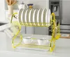 A gold dish rack with plates, cups, and cutlery on a white countertop. Voir les images du produit