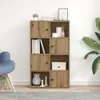 A wooden bookshelf with multiple compartments, some closed with doors and some open, is shown against a white wall. Decorative items like books, vases, and a framed picture are placed on and inside the shelves. A blue chair is partially visible on the left Podgląd zdjęcia produktu