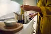 A person is cooking on a modern induction stovetop. Voir les images du produit
