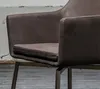 Close-up view of a brown leather armchair with a metal base. Produktbild-Vorschau