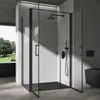 A modern black corner shower cabin with a black shower tray and black fixtures, set against a textured gray wall. Natural light streams in from a large window on the left, illuminating the shower and casting shadows. Voir les images du produit
