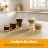 Several cups of coffee and milk foam are arranged on a wooden table in a kitchen setting. Produktbild-Vorschau