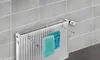 A radiator with a towel rack attached, holding two towels, in a tiled bathroom. Anteprima dell’immagine prodotto