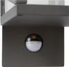 A close-up view of a motion sensor attached to a dark-colored fixture, likely part of an outdoor light. Podgląd zdjęcia produktu