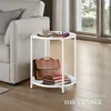 A white side table with a leather briefcase and books on it, placed next to a sofa in a living room. Náhled obrázku produktu
