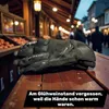 Gloves on a wooden table in front of a market stall with people in the background. Produktbild-Vorschau