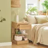 A bedside table with items on and around it, next to a bed. Produktbild-Vorschau