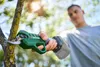 A person is using a cordless pruning shear to trim a tree branch outdoors. Produktbild-Vorschau