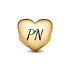 A golden heart-shaped charm with the letters 'PN' engraved on it, isolated on a white background. Podgląd zdjęcia produktu