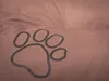 A close-up of a brown dog bed with a gray paw print. Produktbild-Vorschau