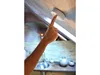 A hand is pressing the test button on a smoke detector mounted on a ceiling. Produktbild-Vorschau