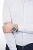 A man wearing a light blue dress shirt and dark blue jeans, with a silver watch on his left wrist. Náhled obrázku produktu