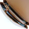Close-up view of the interior of a brown leather handbag, showing zippered compartments. Produktbild-Vorschau