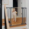 A baby stands behind a baby gate on a staircase. Voir les images du produit