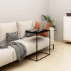 A laptop is placed on a small black side table next to a cream-colored sofa with decorative pillows and a throw blanket. Náhled obrázku produktu