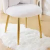 A close-up view of the legs and seat of a white fluffy chair with gold legs, resting on a white fluffy rug. Podgląd zdjęcia produktu