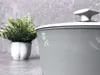 A close-up of a gray pot with a white lid, next to a potted plant. Podgląd zdjęcia produktu
