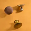 Three cabinet knobs are arranged on an orange textured surface. Produktbild-Vorschau