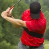 A golfer is shown mid-swing, wearing a red shirt and a black cap. A black arm brace is visible around their torso. Voir les images du produit