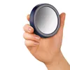 A hand holding a small, round, blue mirror with a gray rim. Anteprima dell’immagine prodotto