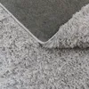 A close-up view of the underside and fluffy texture of a light gray rug. Produktbild-Vorschau
