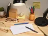 A desk with a lamp, glasses, pens, and paper. Produktbild-Vorschau
