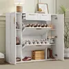A white shoe cabinet with multiple shelves and drawers, filled with shoes and some decorative items, placed in a room. Podgląd zdjęcia produktu