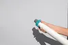 A hand holding a white ribbed hose with a blue and gray connector against a light gray background. Produktbild-Vorschau