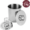 A stainless steel meat cooker with its lid and a separate spring-loaded component. Produktbild-Vorschau